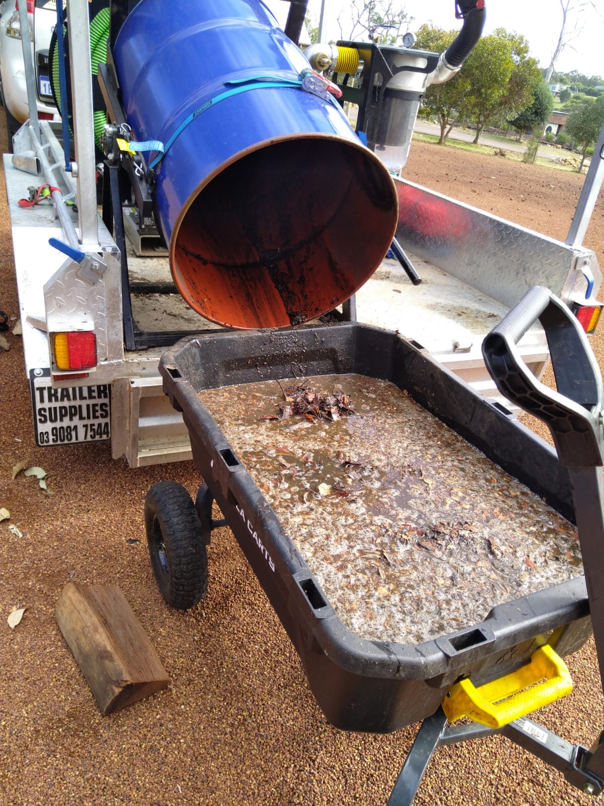Gutter vacuum trailer tipping wet leaves and sludge into a cart